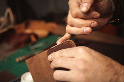 Lubricates edges with cream. tanner makes leather wallet, professional craftsman, business. 