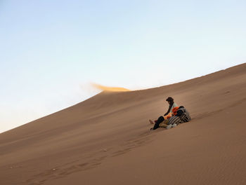 People riding in desert against clear sky