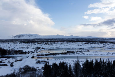 Scenic view of lake by snowcapped mountains against sky