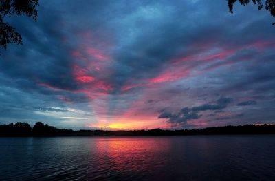 Scenic view of lake against dramatic sky during sunset