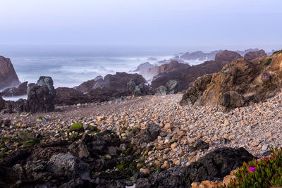 Scenic view of rocky shore and sea against sky