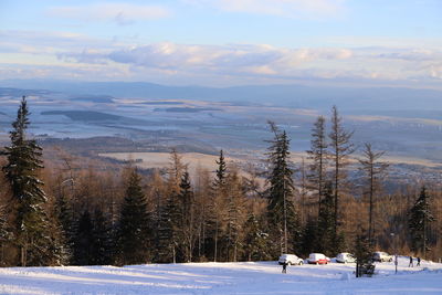 Snow covered landscape against sky during sunset