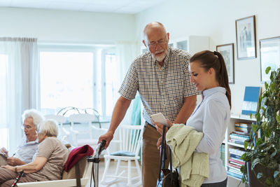 Young woman showing mobile phone to senior man at nursing home