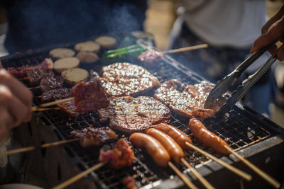 Cropped hand of man preparing food on barbecue grill