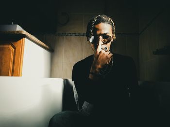 Portrait of young man wearing sunglasses sitting at home