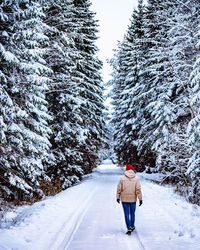 Rear view of woman walking on snow covered land