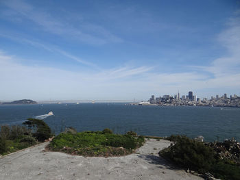 Scenic view of sea by city buildings against sky