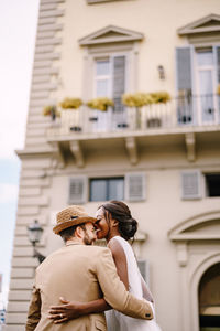 Couple embracing against building in city