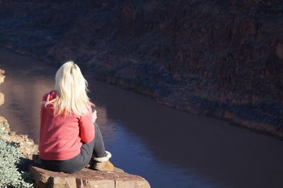 Rear view of woman sitting on rock