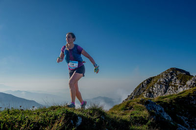 Full length of woman standing on mountain against clear blue sky