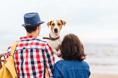 Rear view of man with dog against sea