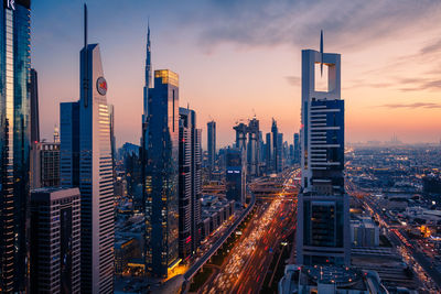 Panoramic view of illuminated city buildings against sky during sunset