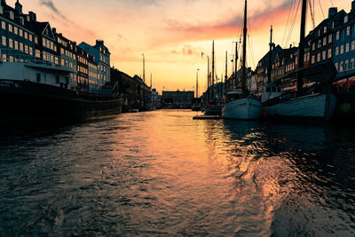 Sailboats moored in sea against sky during sunset