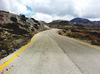 Empty road by mountains against sky