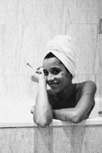 Portrait of smiling young woman sitting against wall