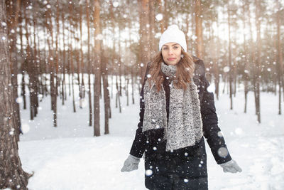 Happy woman with arms outstretched in snow during winter