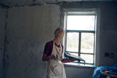 Young woman painting wall