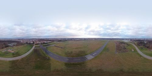 Panoramic shot of road amidst field against sky