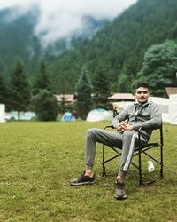 Full length of young man sitting on chair outdoors