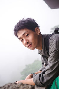 Portrait of young man standing by railing