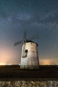 Traditional windmill on field against sky at night
