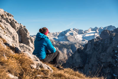 Man standing on rock against blue sky