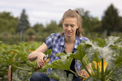 Young woman working as vegetable grower or farmer in the field