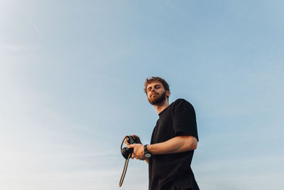 Low angle view of man with camera standing against sky