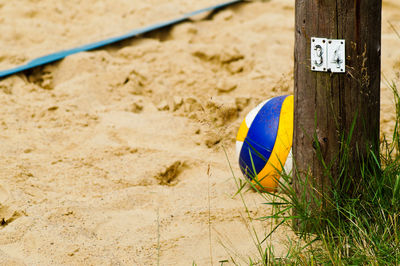 Volleyball by wooden post on sand at beach