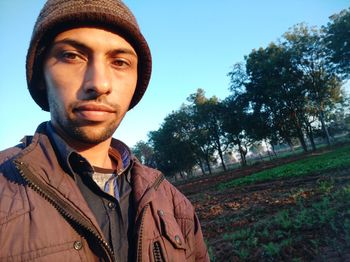 Portrait of young man standing against trees and plants