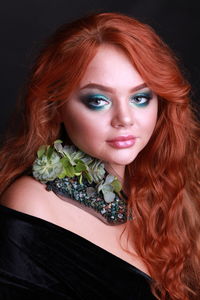 Portrait of sensuous young woman wearing flower necklace against black background