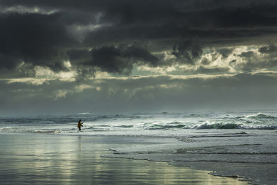 Man fishing in sea against sky