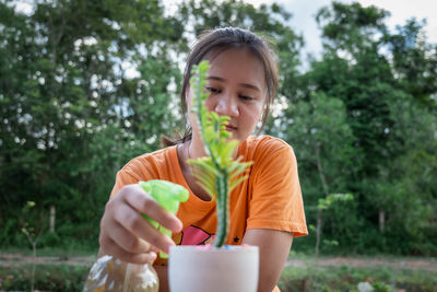 A woman waters her ornamental plants by spraying water to freshen up her model's face