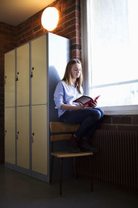 Schoolgirl studying by window in locker room