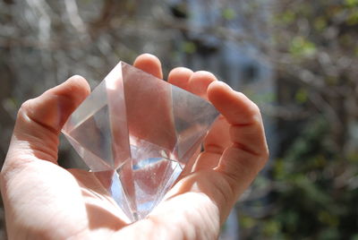 Cropped image of hand holding diamond shaped glass decoration
