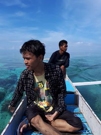 Friends travelling by boat in sea against sky