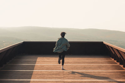 Rear view of man walking on boardwalk