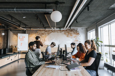 Multiracial male and female entrepreneurs working on computers while sitting at desk in office