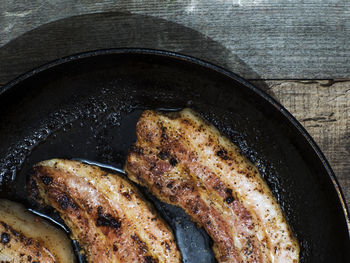 Close-up of pork in container on wooden table