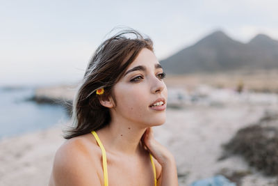 Carefree young woman in yellow bikini on sand at beach