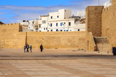 People in front of historic building against sky