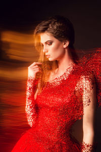 Beautiful fashionable woman in red dress photographed with mixed light