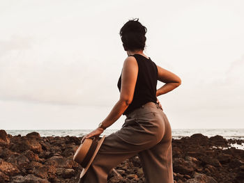 Woman looking at sea shore against sky