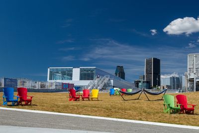 Road by buildings against blue sky in city