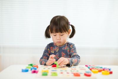 Full length of cute girl playing with ball on table