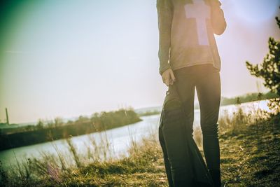 Rear view of woman standing on grass by lake