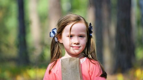 Close-up portrait of girl with paper bag against trees in forest
