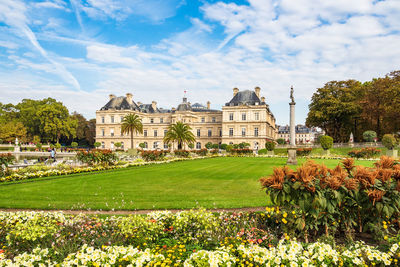 View of lawn and buildings against cloudy sky