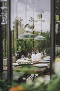 Table setup for dinner party in back yard greenhouse seen through glass window