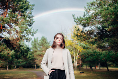Portrait of young woman standing against trees